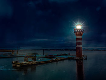 Illuminated ship moored at harbor against sky at night