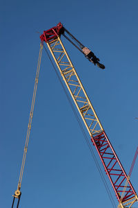 Low angle view of crane against clear blue sky