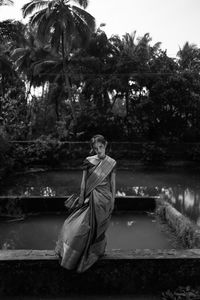 Rear view of woman sitting on railing