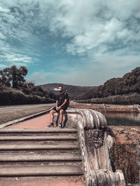 Full length of man smoking while sitting against sky