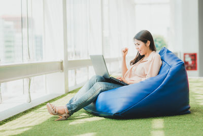 Businesswoman using laptop while sitting on bean bag on office