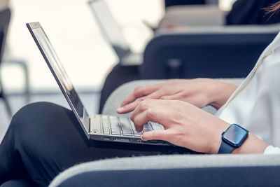 Young millennial woman typing on laptop. hands only in frame. day light dynamic workplace.