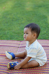 Cute boy looking away while sitting on grass