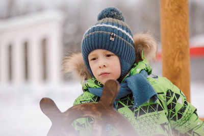 Little boy walks on the playground on a frosty winter day. the kid plays with the steering wheel 