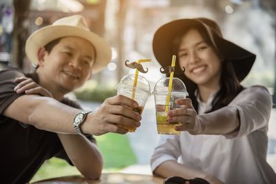 Smiling couple holding juice sitting at restaurant