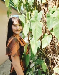 Portrait of young woman standing amidst plants