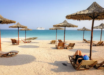Lounge chairs and parasols on beach against sky