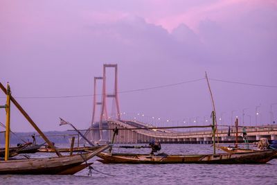 Sailboats moored on sea against sky at sunset