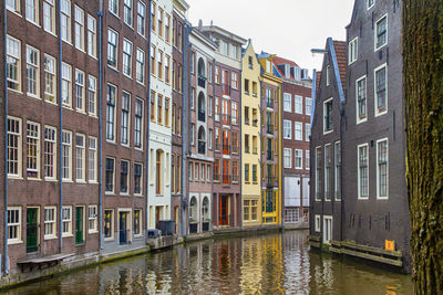 Canal amidst buildings against sky in city