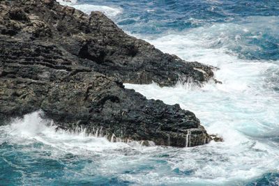 High angle view of waves crashing rock