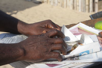Cropped hands of man wrapping food in paper on table