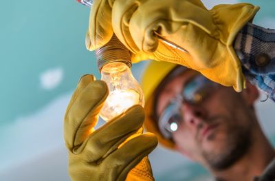 Close-up of man repairing illuminated light bulb