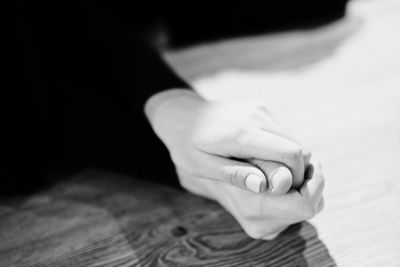 Close-up of hands clasped on table