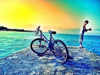 Bicycles on beach against sky during sunset