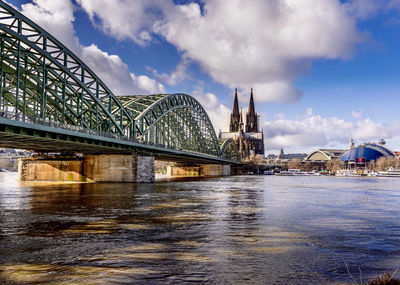 Bridge over river against cloudy sky