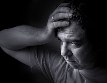 Close-up depressed man against black background