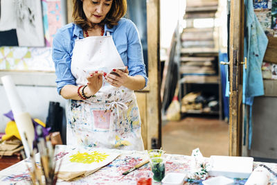 Female artist checking phone in workshop