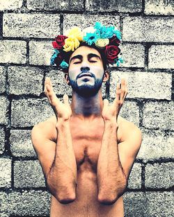 Midsection of shirtless man standing against wall