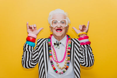 Portrait of happy senior woman gesturing against yellow background