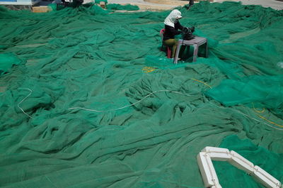 High angle view of woman making fishing net with sewing machine in workshop