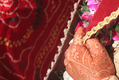 Cropped hand of bride with henna tattoo holding sari