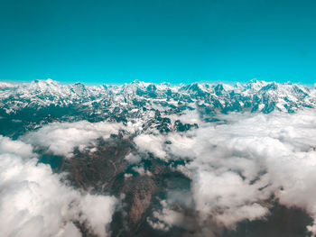 Aerial view of snowcapped mountains against blue sky