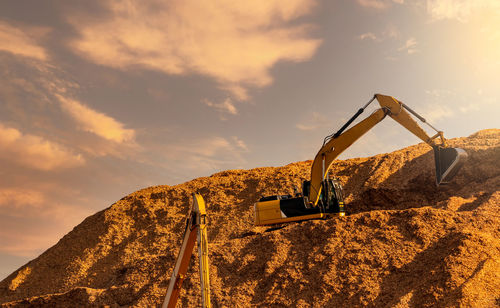 Backhoe working on huge sawdust pile in paper production factory. bucket of digger digging wood