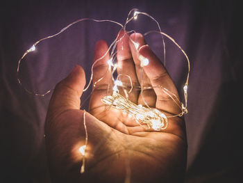 Close-up of hand holding illuminated string light