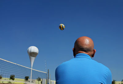 Low angle view of people against clear blue sky