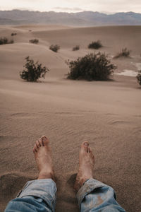 Low section of man relaxing on sand