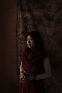Portrait of beautiful young woman standing against wall