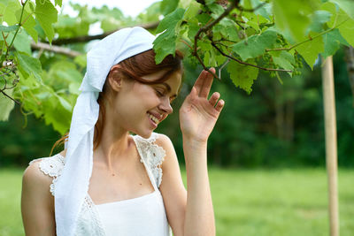 Portrait of young woman standing against trees