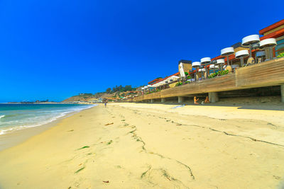 Scenic view of beach against clear blue sky