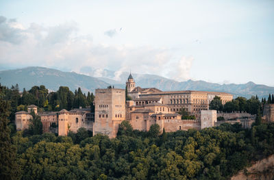 Granada's iconic alhambra. intricate details amid lush greenery against the spanish sky.