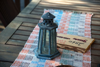 High angle view of antique lantern by plank on table