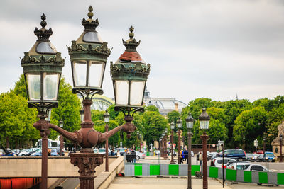 Street light by trees against sky in city