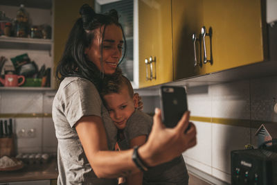 Woman photographing with mobile phone at home