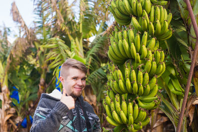 Young man standing by tree against plants