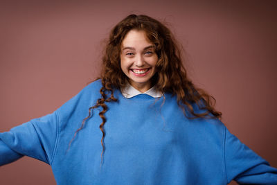 Portrait of young woman standing against wall