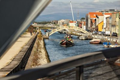 Sailboats on river by buildings in city against sky