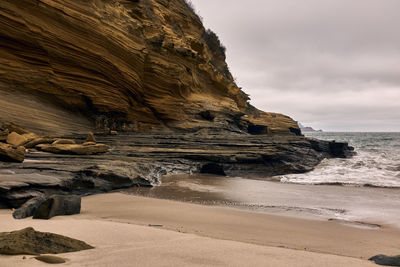 Rock formations on beach against sky