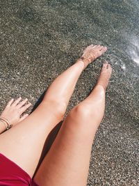 Low section of woman relaxing on sand at beach