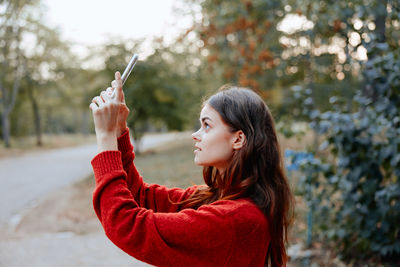 Young woman blowing bubbles while standing outdoors