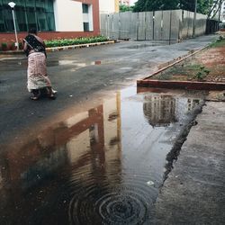 Rear view of woman walking on wet street