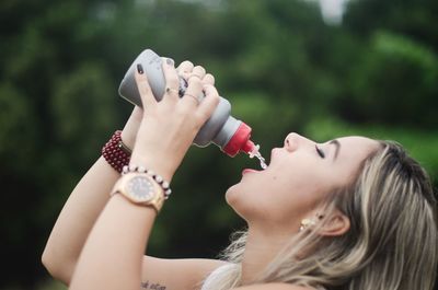 Side view of young woman drinking water