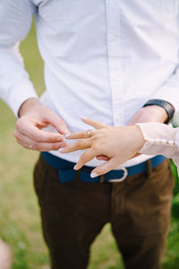 Midsection of groom putting ring in brides finger