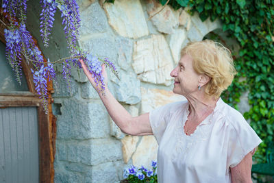 Elderly woman looking at blooming wisteria branches