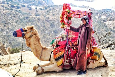 Man standing with camel against mountains