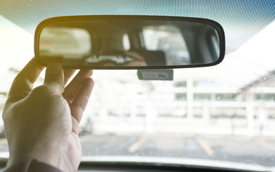 Cropped hand holding rear-view car mirror