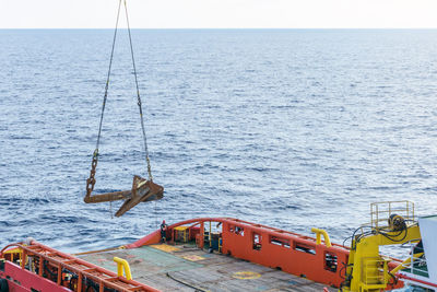 A delta flipper anchor being lifted from a construction work barge onto an anchor handling tugboat